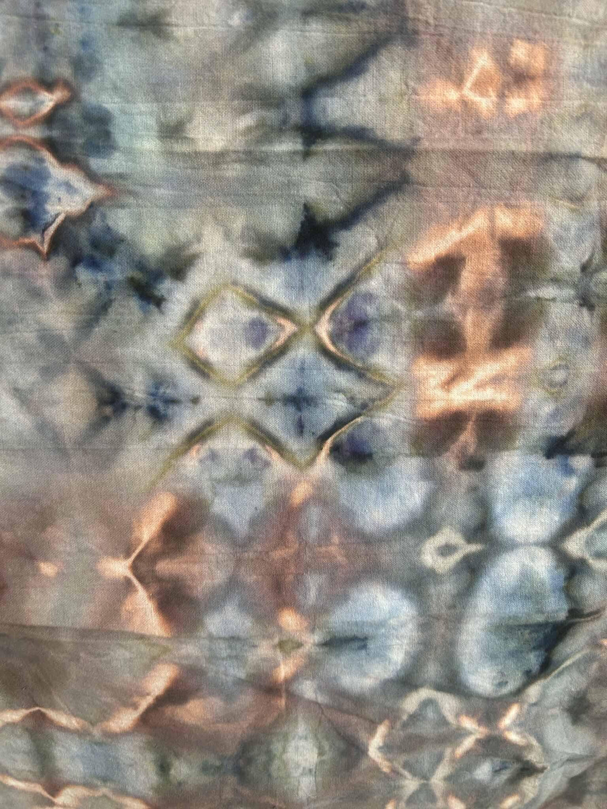 Close-up of ice dye tea towel showing geometric diamond and line pattern in blue and rust