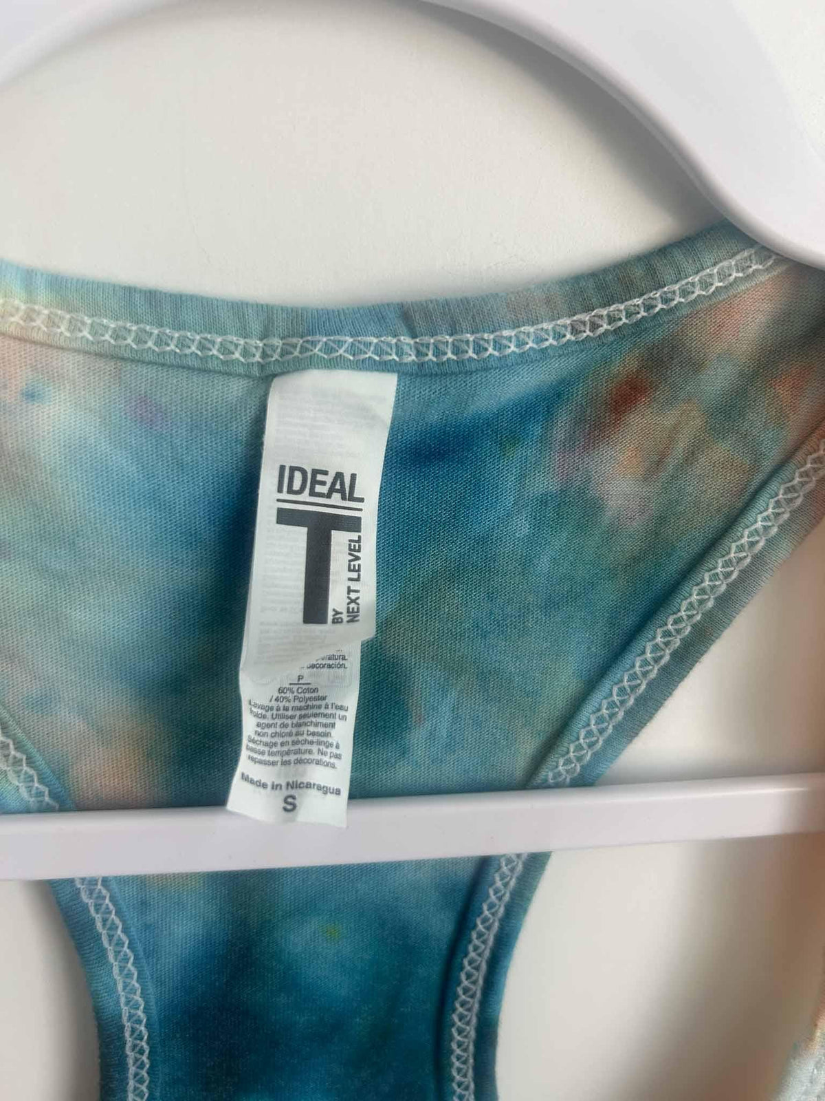 Tank top racerback strap detail with Next Level Ideal T tag in teal tie dye
