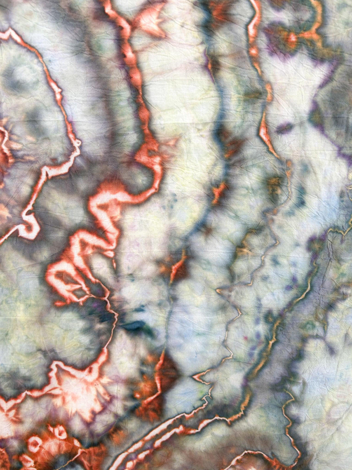 Close-up of ice dyed tea towel showing copper veining and sage green marbled pattern