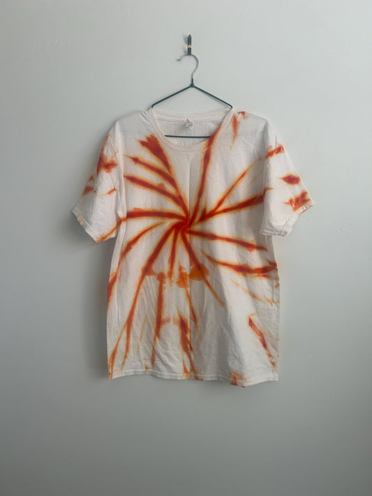Front view of a handmade spiral tie dye Hanes tee in rust and burnt orange on white, hanging on a wall __etsy:7919146028