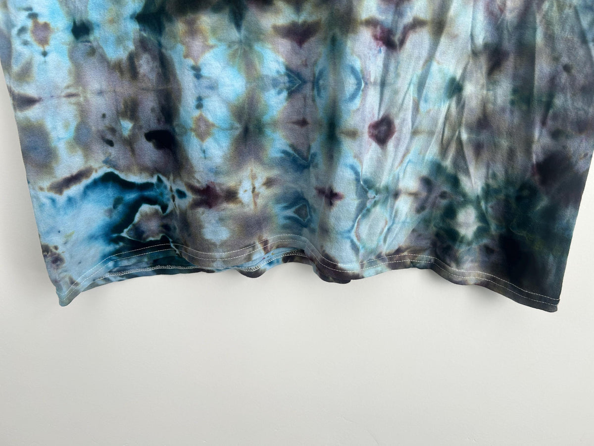 Bottom hem detail of handmade ice dye tie dye shirt showing color saturation and stitching condition