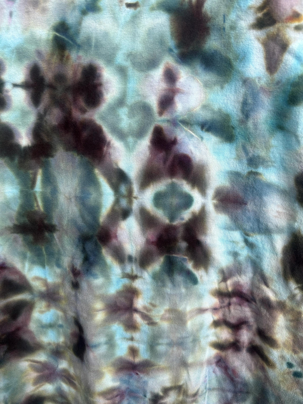 Close up detail of ice dye tie dye pattern showing organic color splits in blue purple and black on cotton fabric