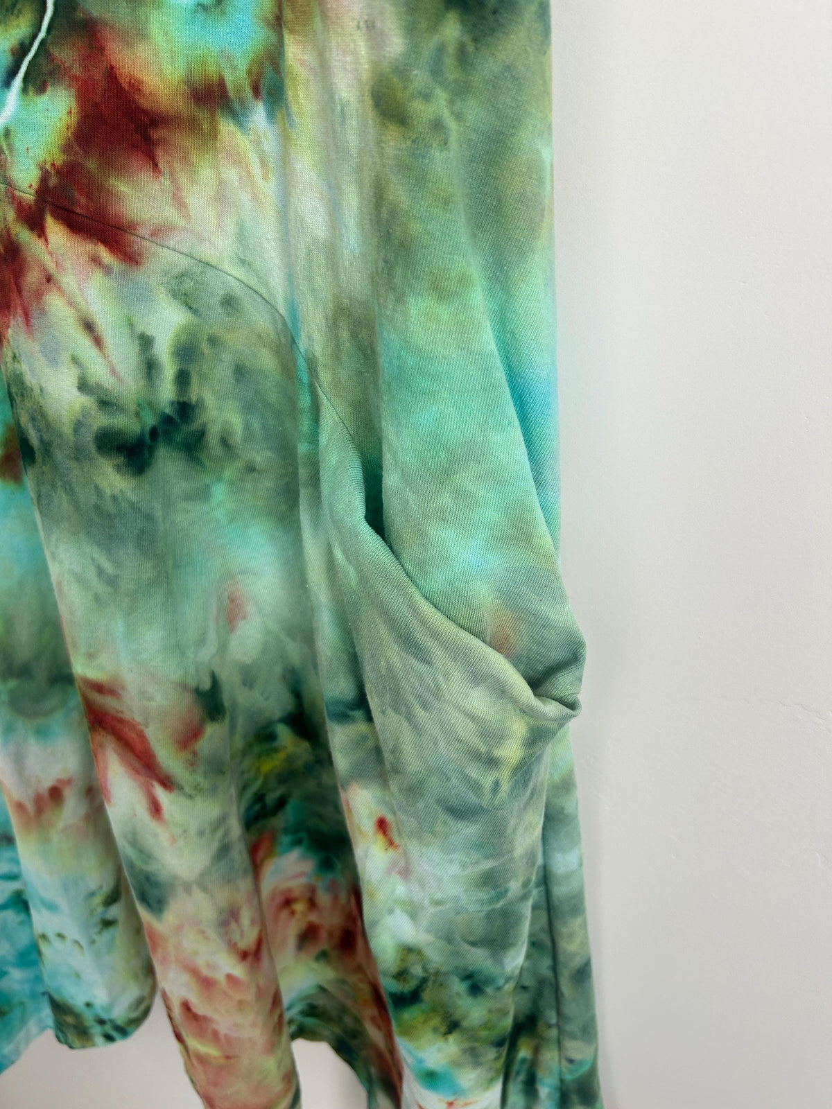 Close-up of ice dyed dress showing geode tie dye lines in purple, green, and teal with organic crackle pattern with a pocket.