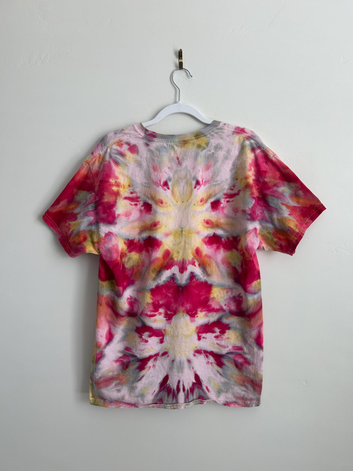 Back view of a hand-dyed ice dye t-shirt showing a stunning mirrored raspberry, yellow, and grey kaleidoscope pattern. One-of-a-kind artisan cotton tee, size L.