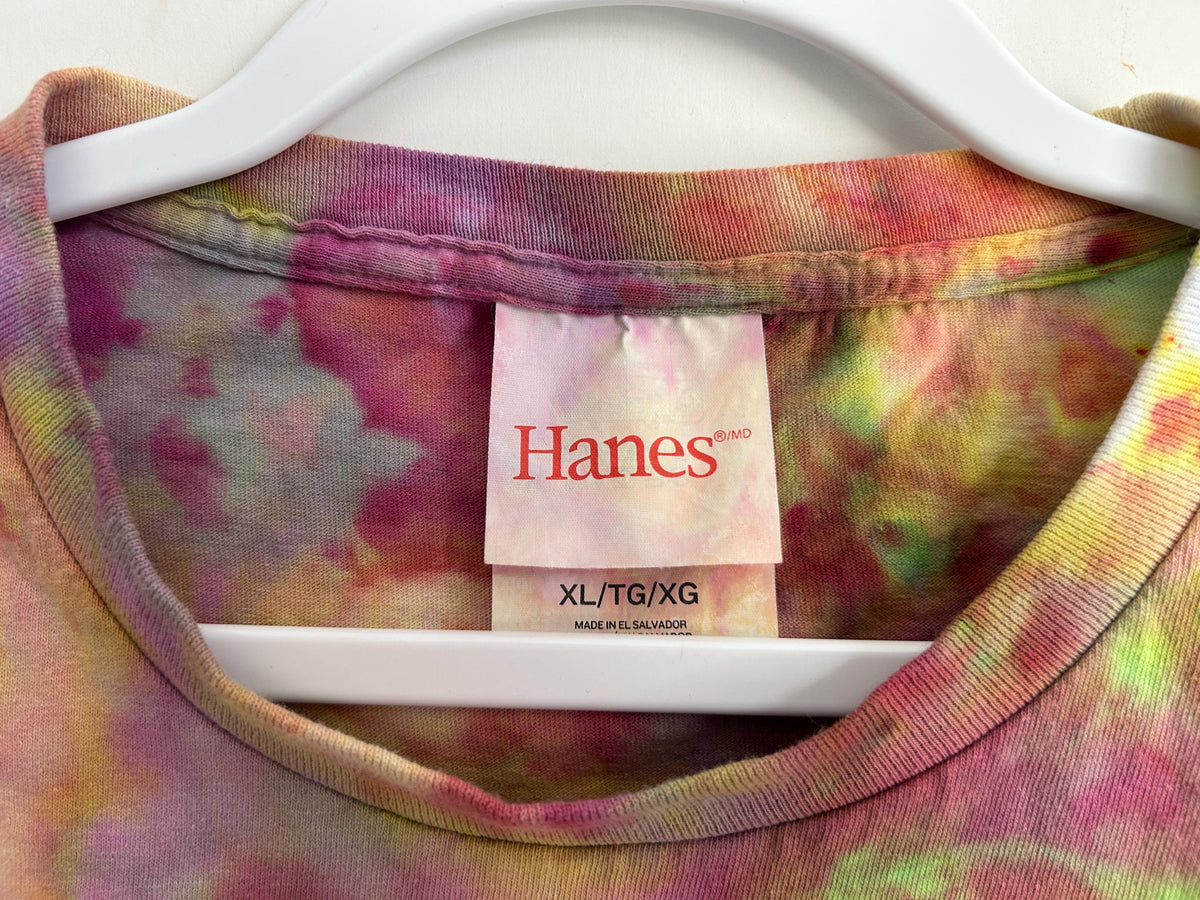 Close-up of Hanes XL tag on ice dyed t-shirt showing tie dye colors of pink, yellow-green, and magenta on collar