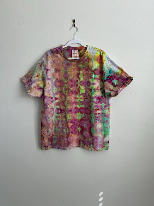 Ice dye t-shirt in XL hanging on white hanger, kaleidoscope pattern in magenta, lime green, mint, coral, and gold on white background