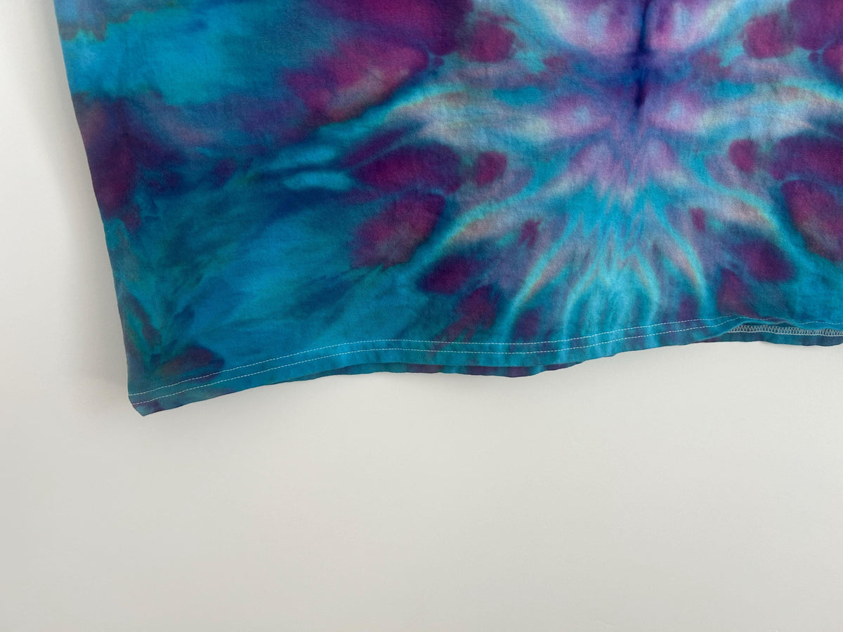 Close-up of the shirt hem and lower pattern showing the starburst ice dye detail in teal and plum