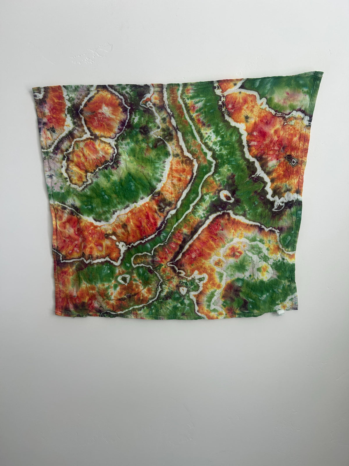 Hand dyed cotton tea towel with geode pattern in green, orange, and red, 27x27 inches