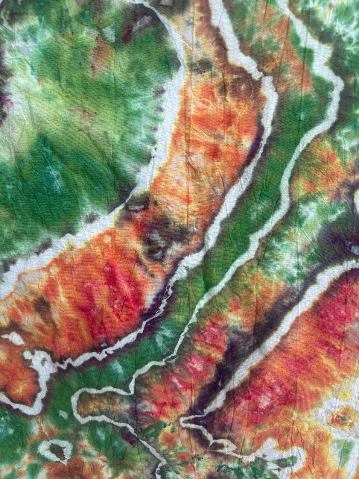 Close up detail of geode hot water irrigation dye pattern on cotton tea towel in green and orange