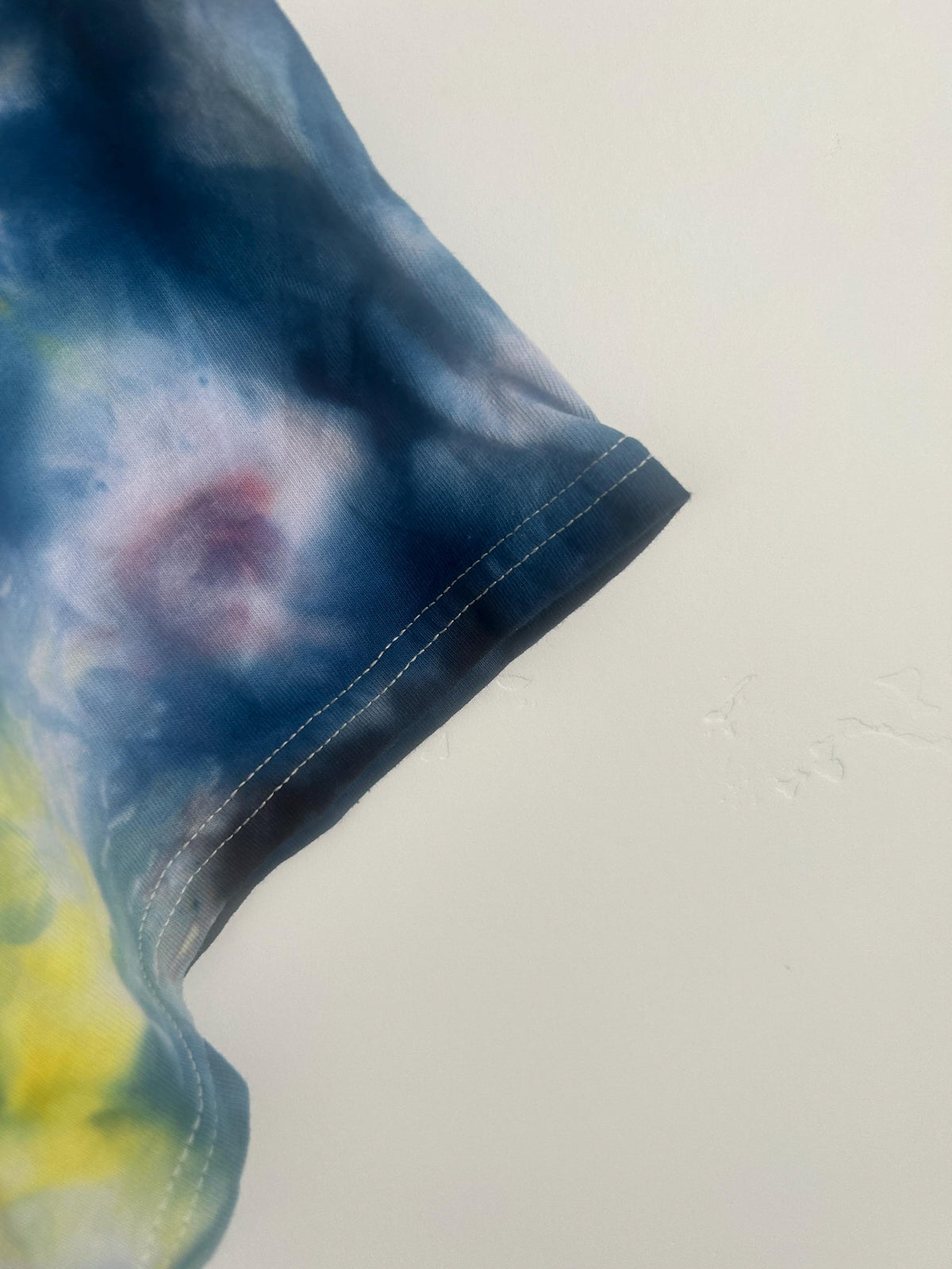 Close-up of sleeve hem showing deep navy dye saturation and white contrast stitching