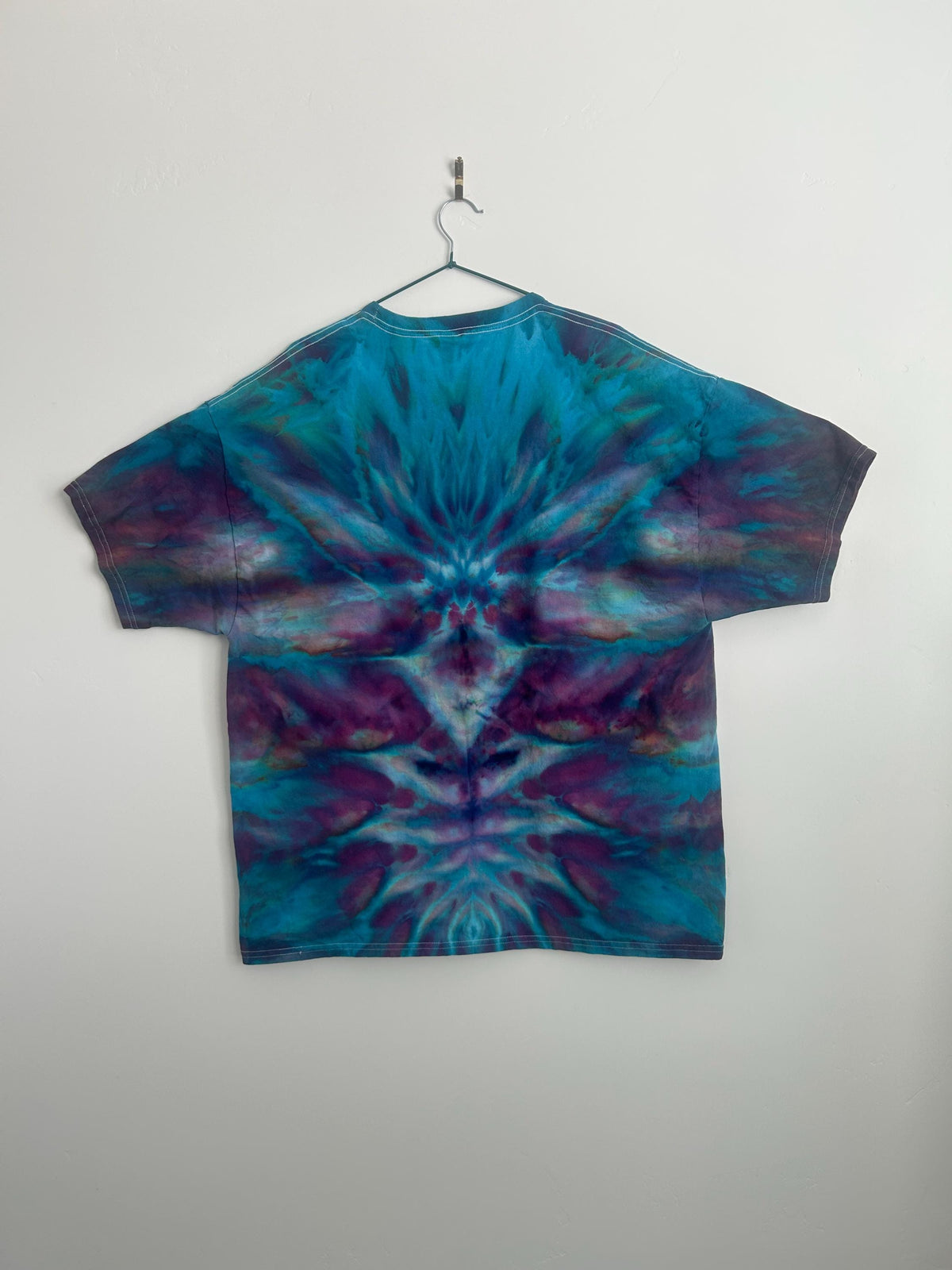 Back view of the shirt showing the full mirrored ice dye pattern in teal and plum