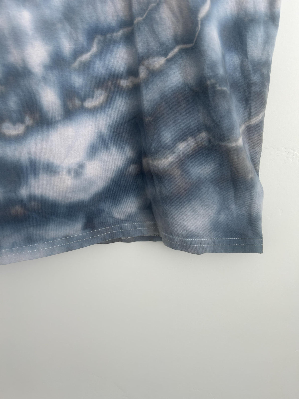 Hem detail of ice dye geode t-shirt in slate gray