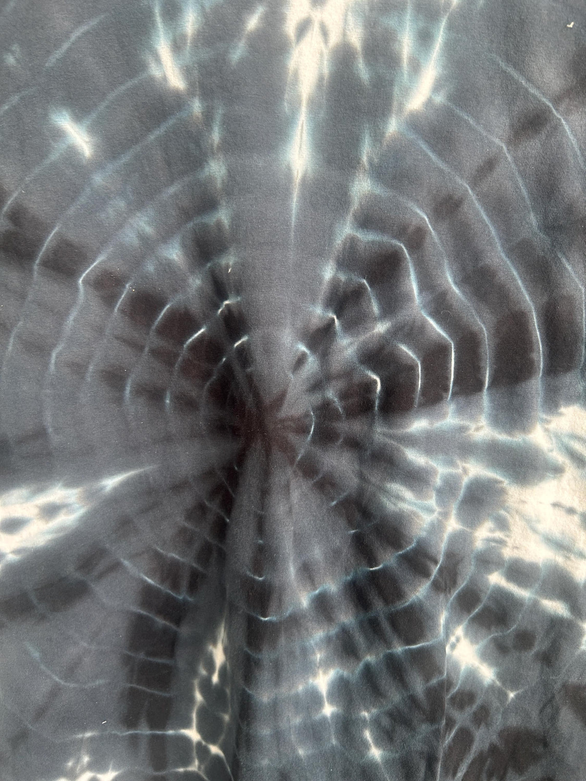 Close up detail of bullseye tie dye pattern showing concentric rings and starburst center in black and white