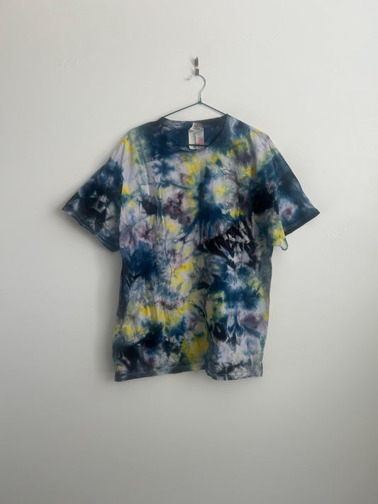 Front view of a handmade ice dye tee in navy, yellow, lavender, and plum on a hanger against a white wall