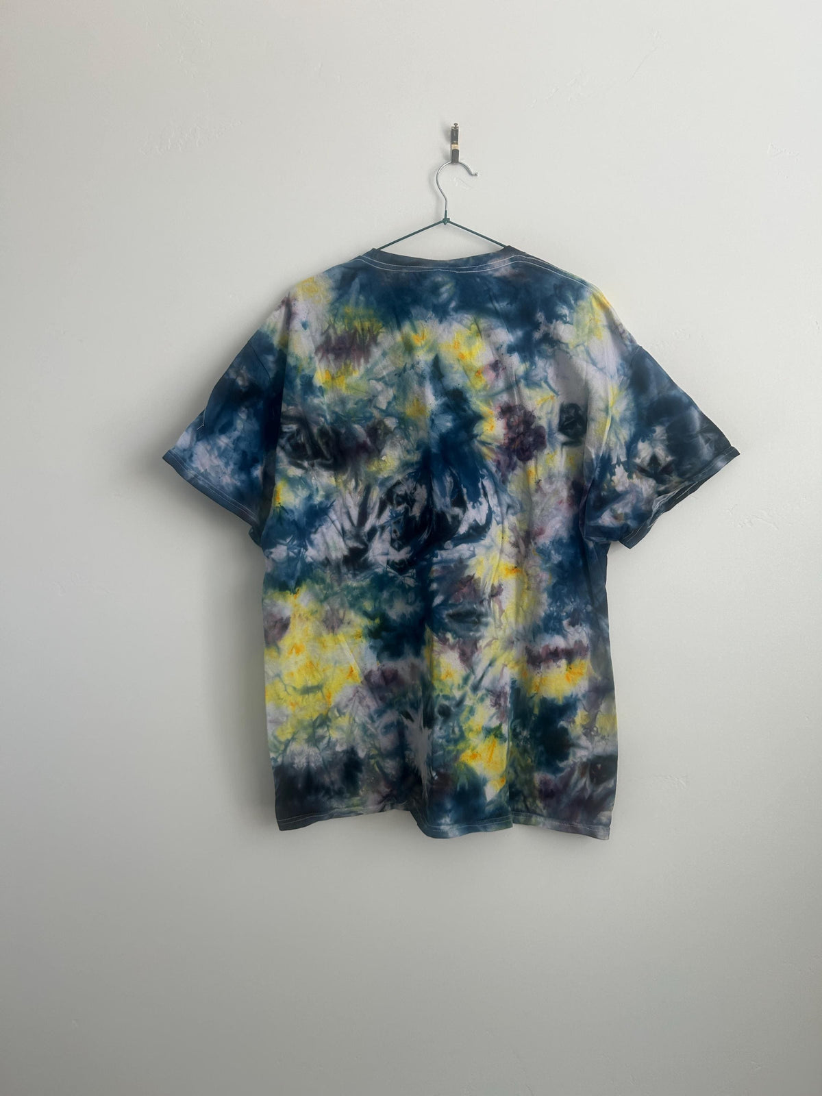 Back view of handmade ice dye tee showing full color coverage in navy, yellow, and purple tones