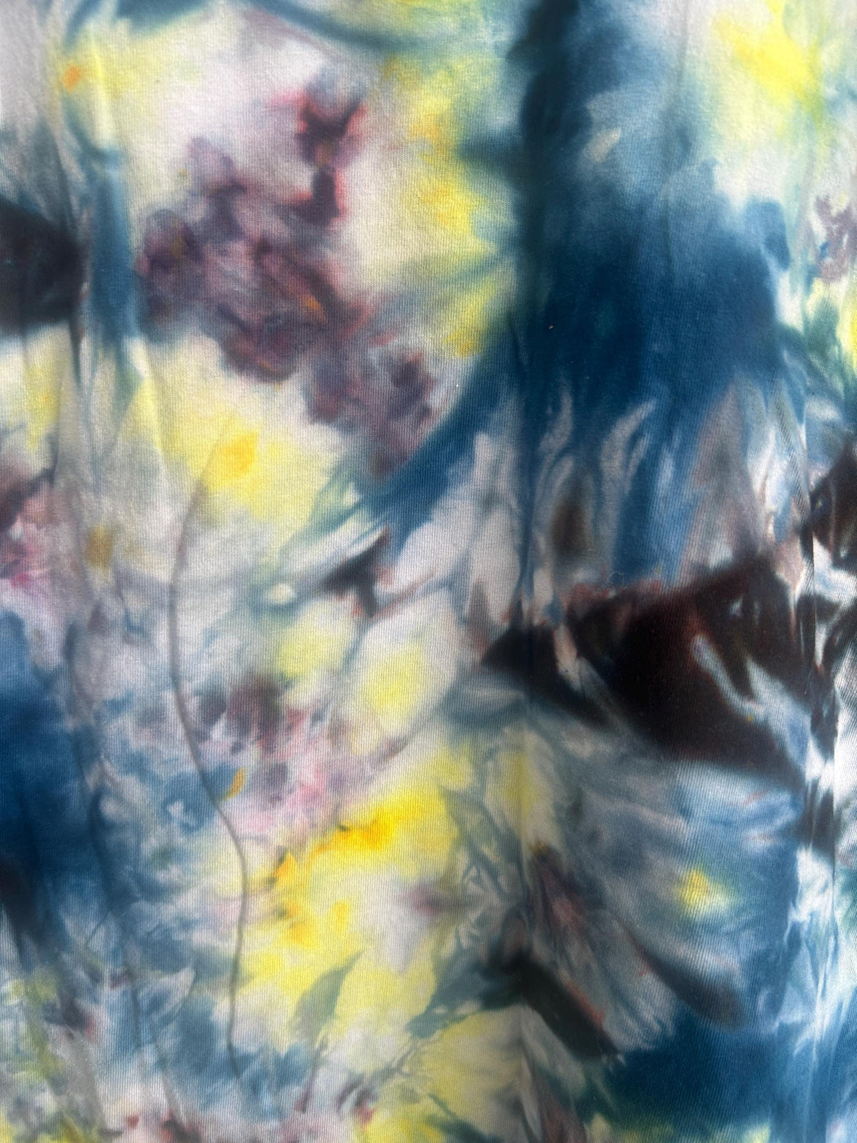 Close-up detail of ice dye pattern showing navy, yellow, lavender, and plum color blending
