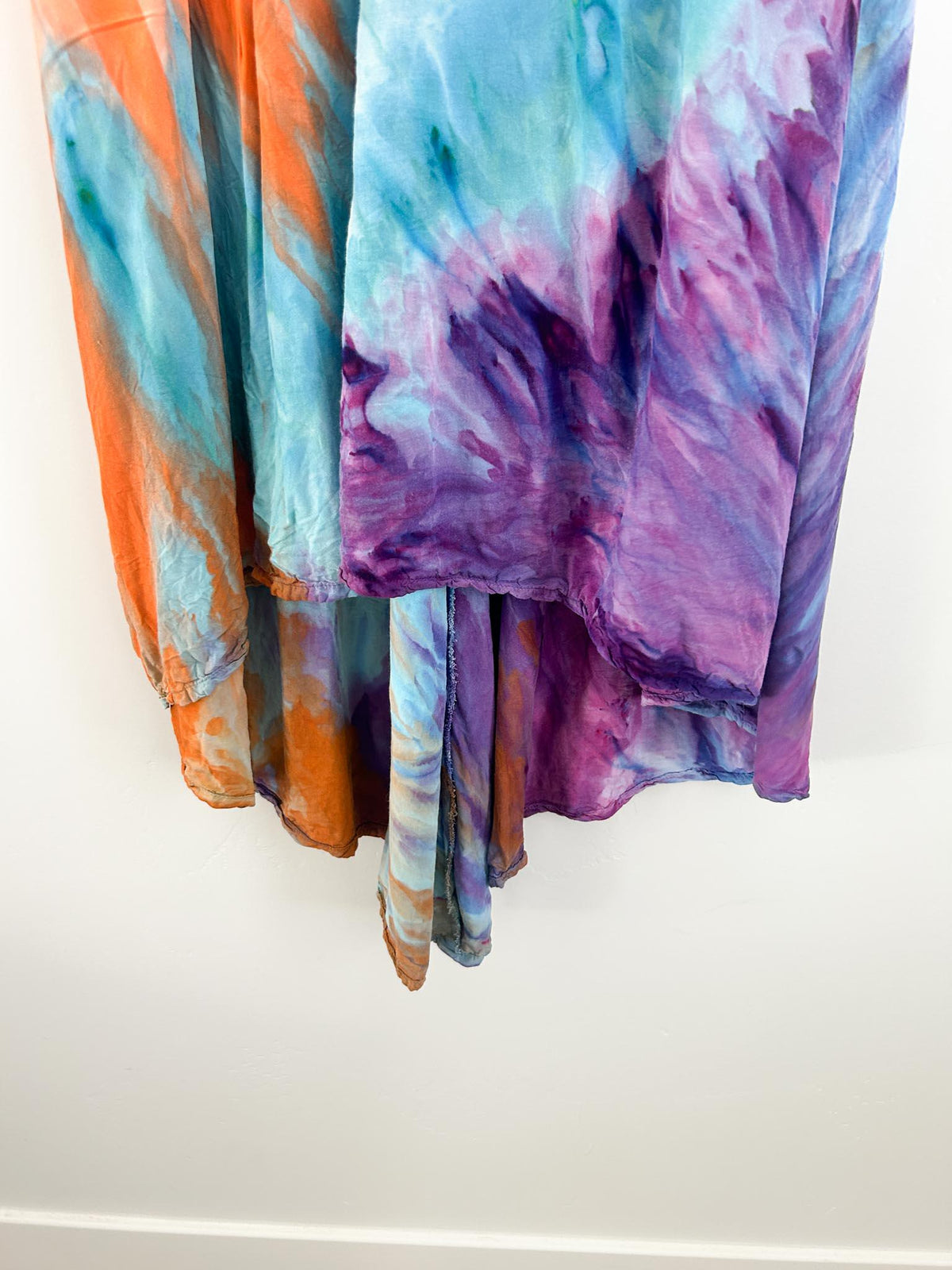 Bottom hem of rayon tie dye dress showing orange, blue, and deep purple sunburst rays