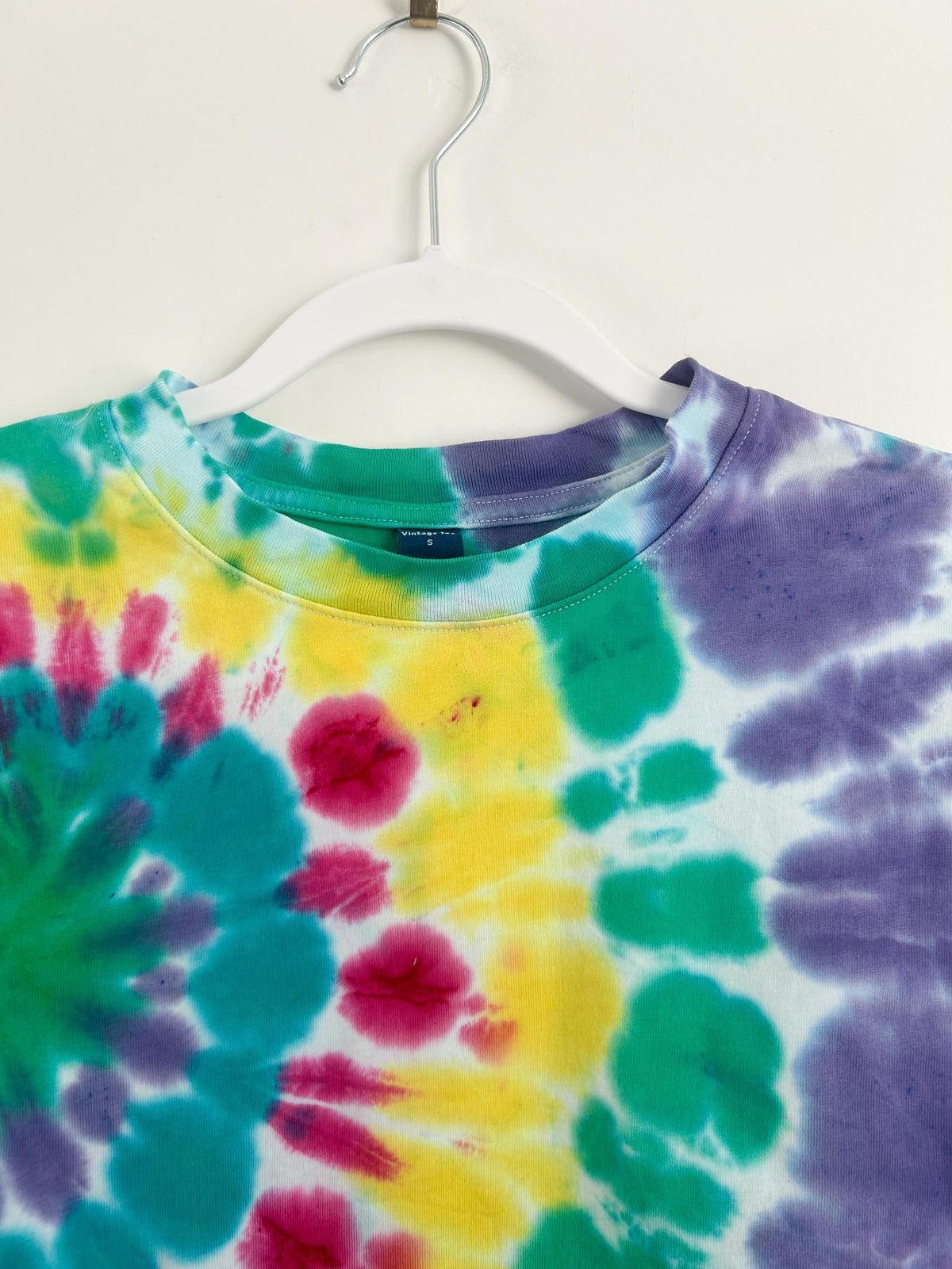 Crew neckline and shoulder detail of rainbow spiral tie dye boxy crop top