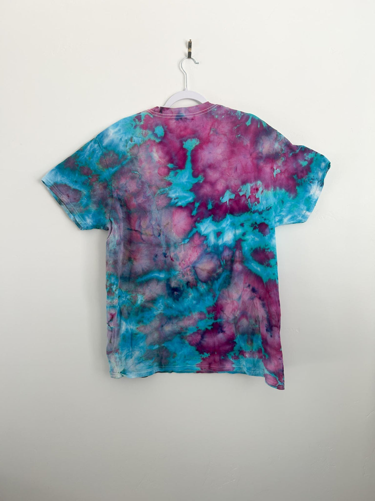 Back of handmade cotton candy ice dye t shirt in size XL on white hanger, pink magenta and teal watercolor blend