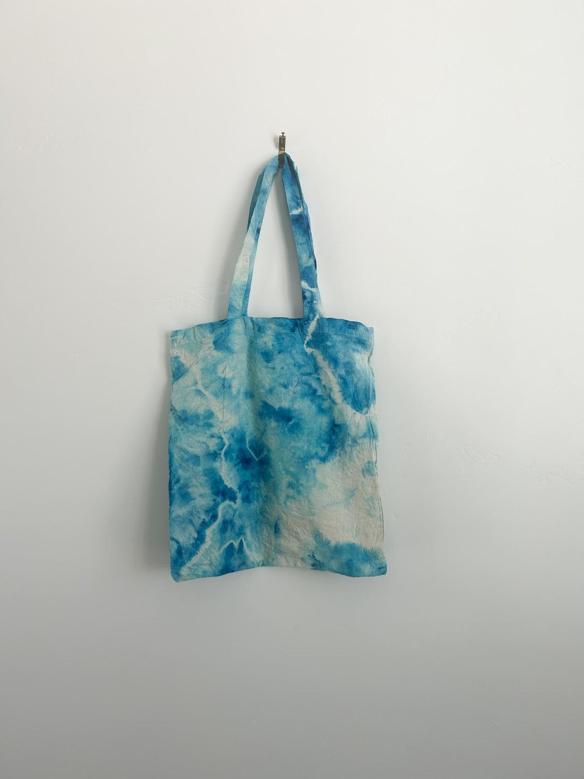 Back of blue ice dye canvas tote bag showing soft and bright blue tie dye blooms on cotton