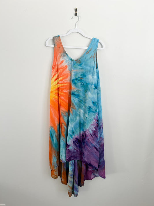 Front of handmade tie dye sundress in size medium on white hanger, sunburst pattern in orange, yellow, blue, and purple