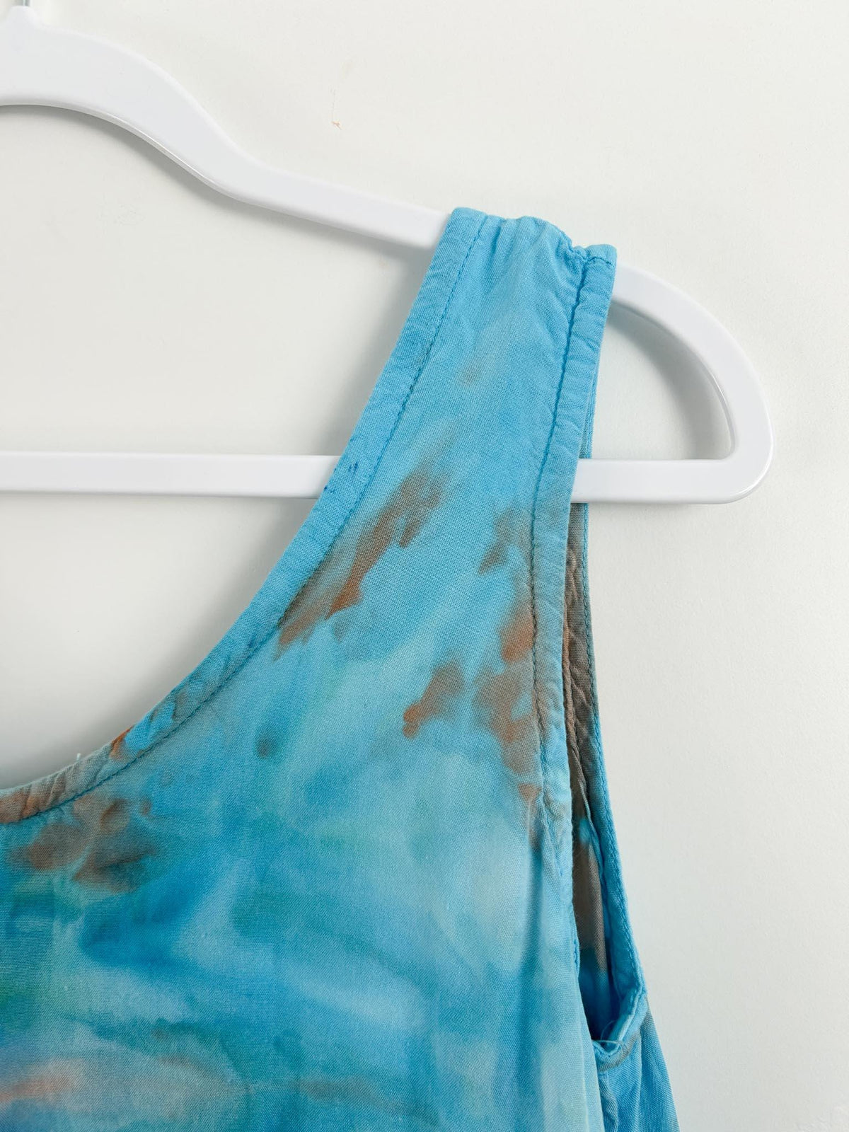Shoulder strap and V neckline detail of tie dye dress in blue, teal, and rust tones