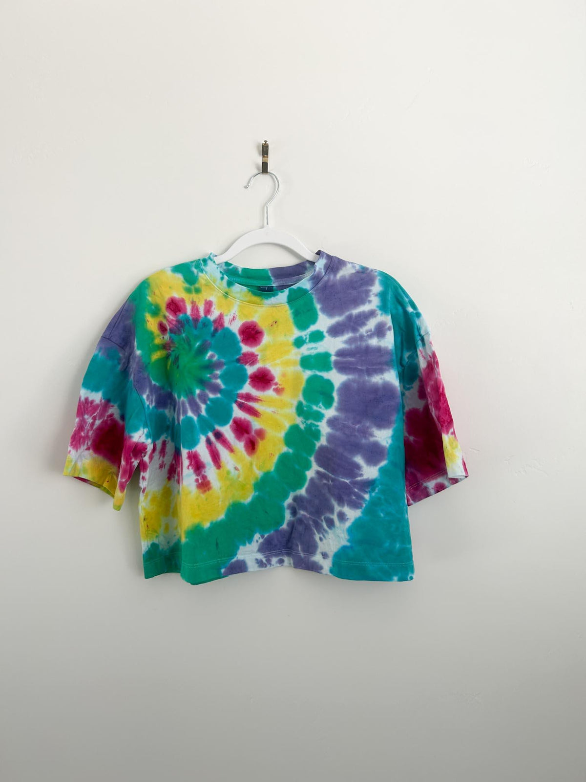 Full front of rainbow spiral tie dye boxy crop top in size small on white hanger
