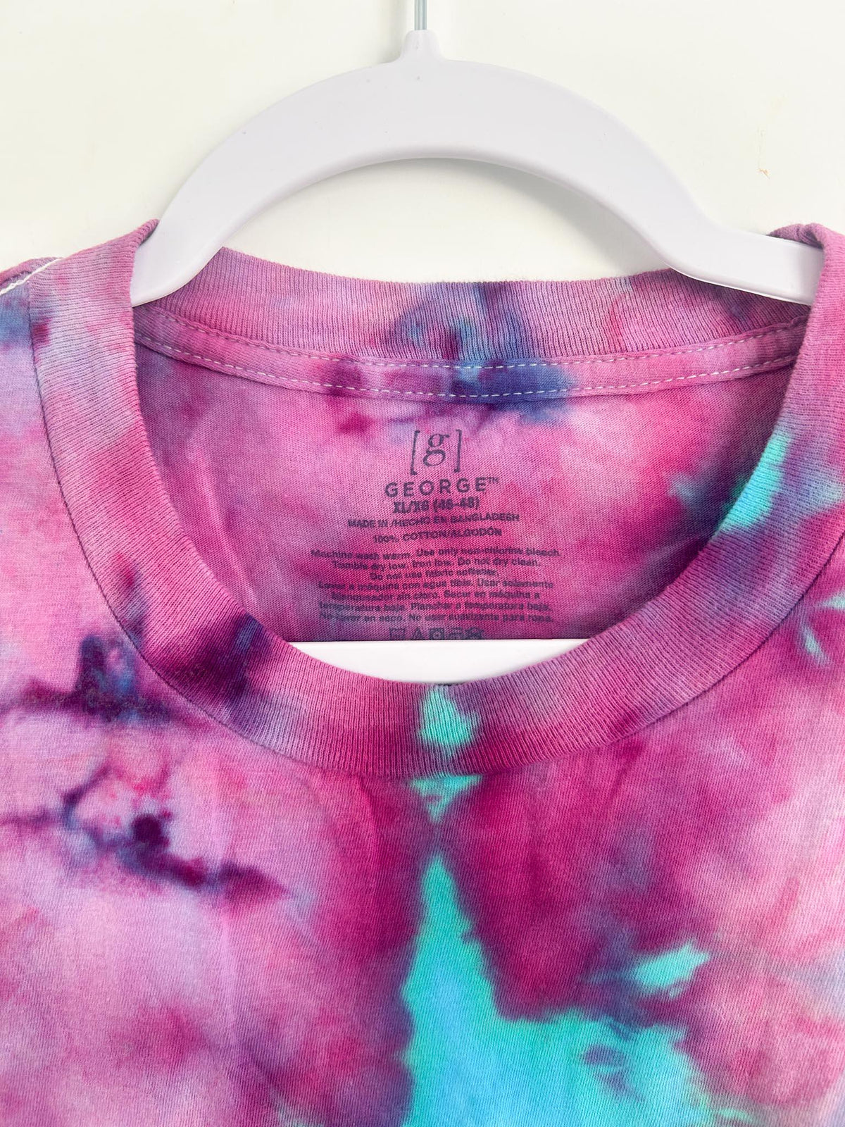 Close up of George brand label showing 100 percent cotton size XL on hand dyed pink and teal t shirt