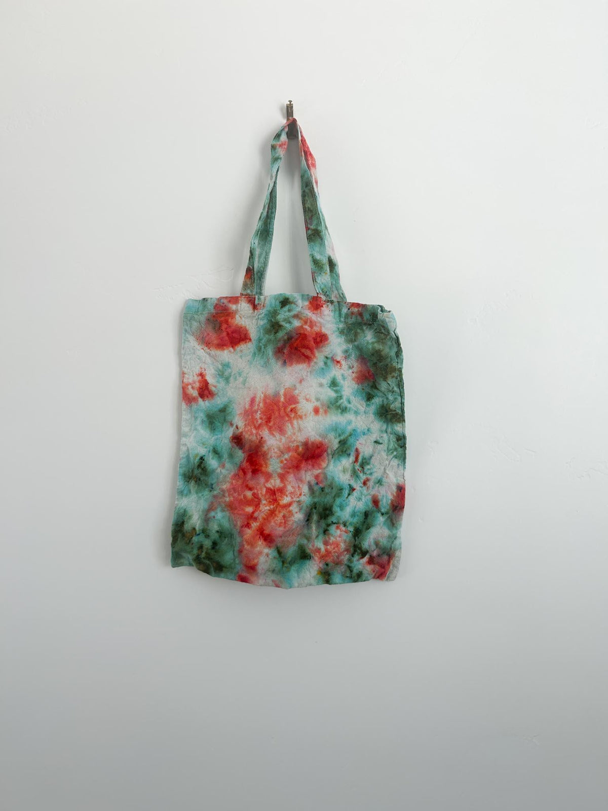 Back view of coral and teal tie dye canvas tote showing watercolor pattern variation