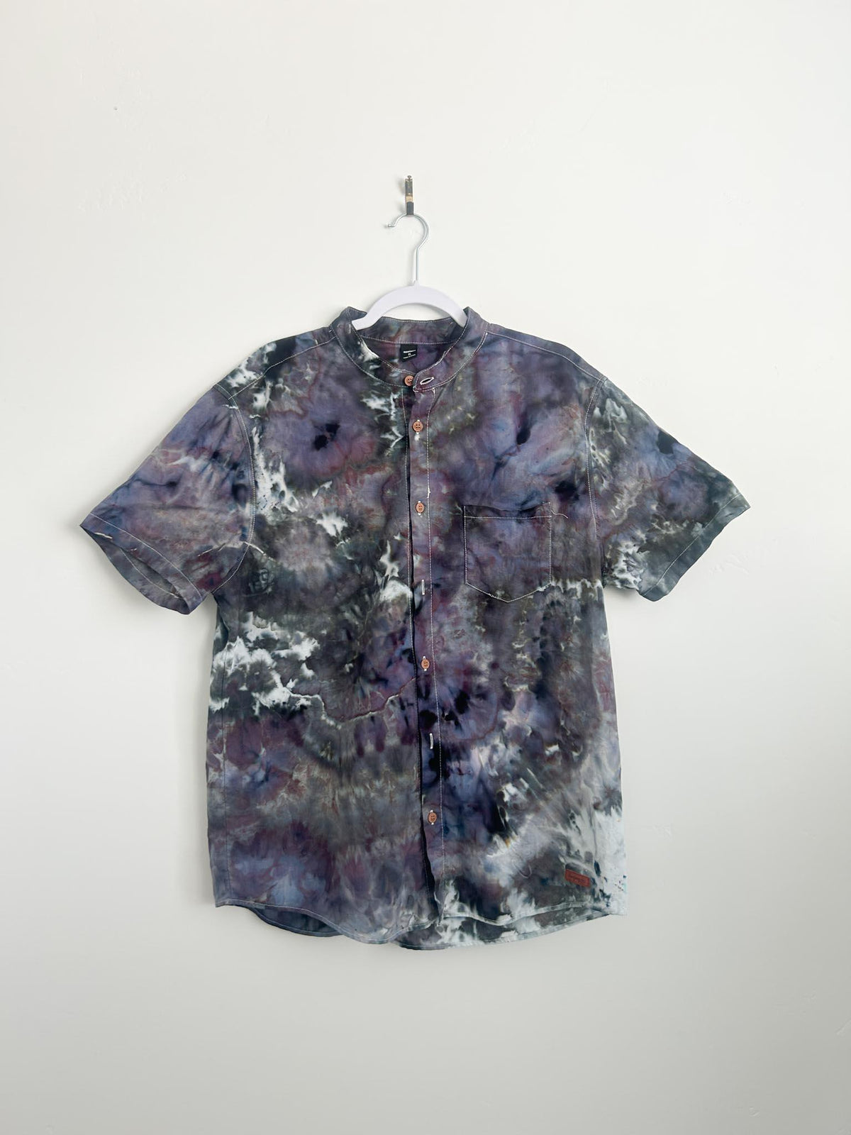 Front of a men's geode ice dye button-down shirt in smoky purple, green, and charcoal on a hanger.