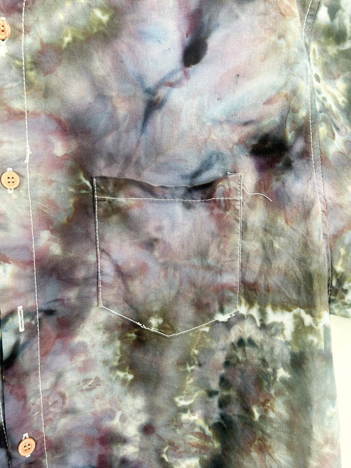 Close-up of the chest pocket on a purple and green geode ice dye shirt.