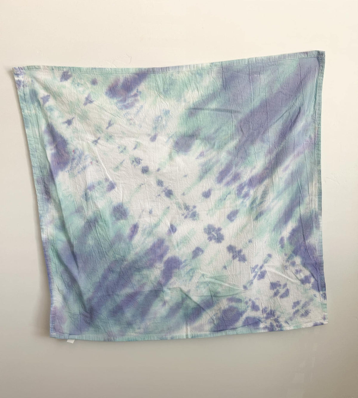 Soft mint and periwinkle pastel tie dye cotton tea towel hanging flat, with a gentle diagonal pattern on white.