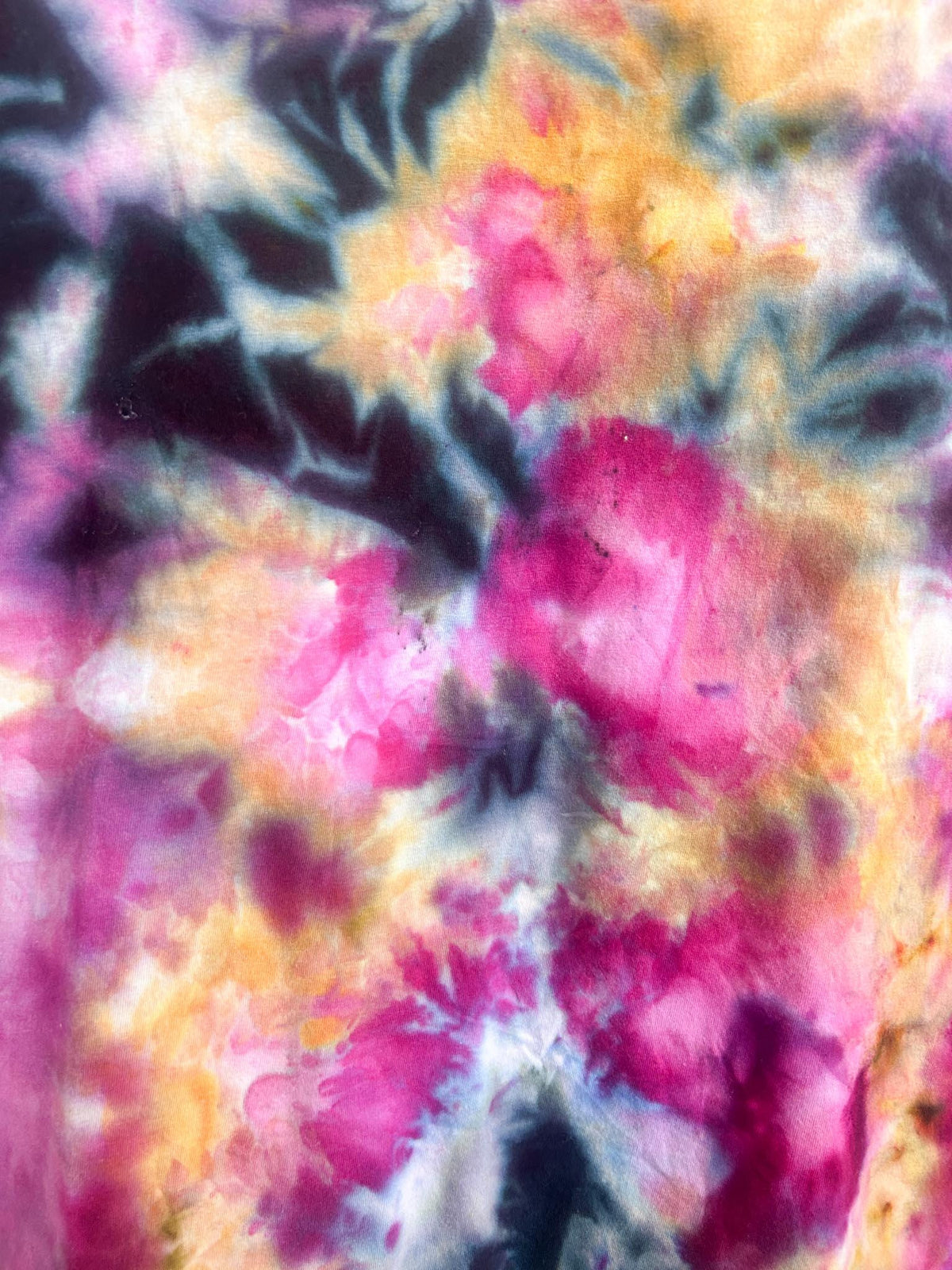 Close-up of the ice dye pattern on a pink and orange t-shirt showing fuchsia and charcoal detail.
