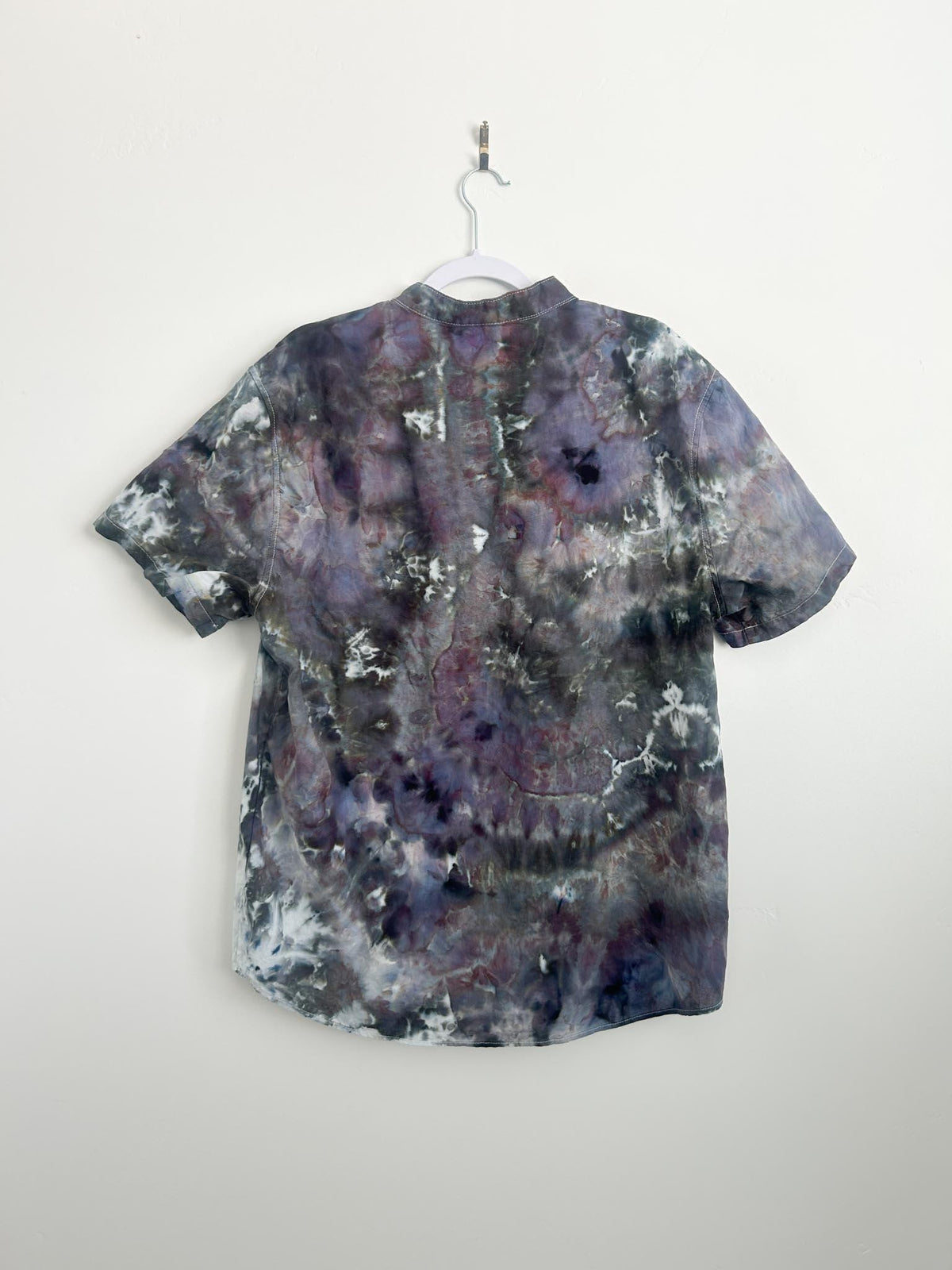 Back of a men's geode ice dye button-down shirt in purple, green, and charcoal on a hanger.