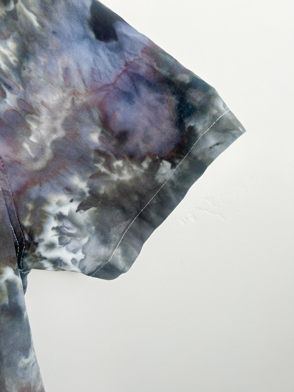 Close-up of the short sleeve hem on a moody geode ice dye button-down shirt.