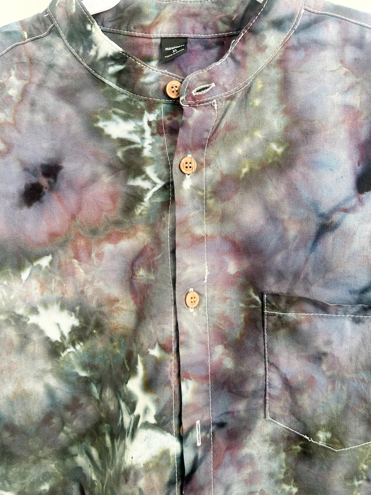 Close-up of the band collar and wood-tone buttons on a geode ice dye button-down shirt.