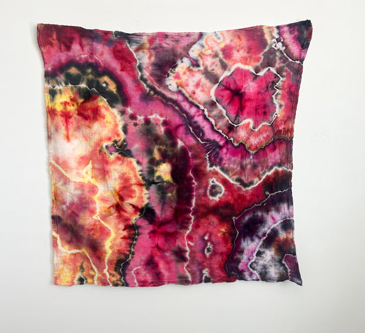 Bold multicolor ice dye tea towel in hot pink, orange, gold, and olive on white, hanging flat.