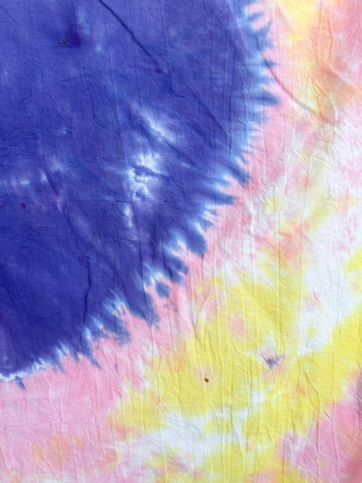 Close-up of the purple heart on a pink and yellow liquid dye tea towel showing the color blending at the edge.