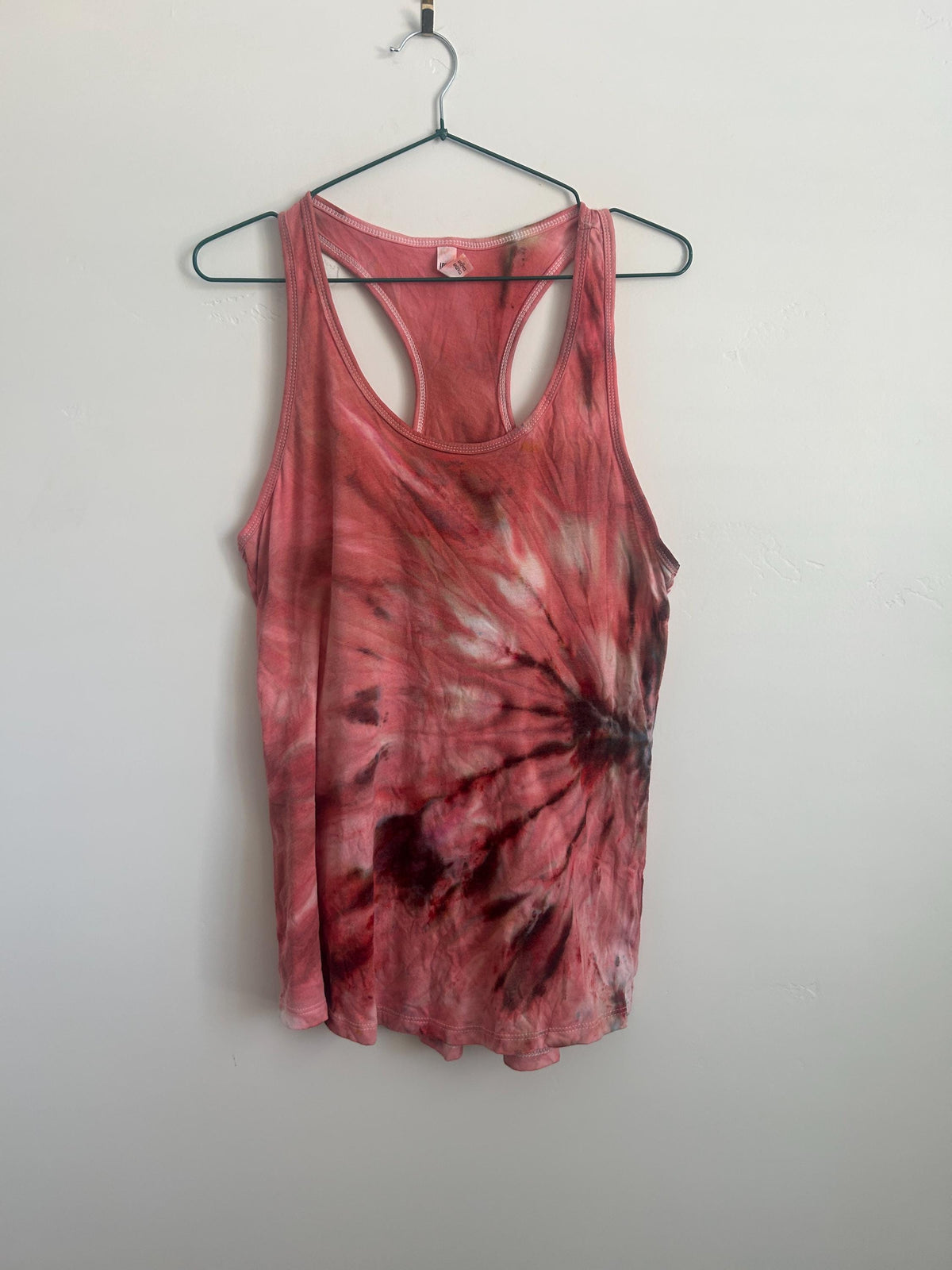 Full front view of a one of a kind Bloodmoon ice dye racerback tank on a hanger, with a maroon and charcoal sunburst fan pattern over coral and rose.