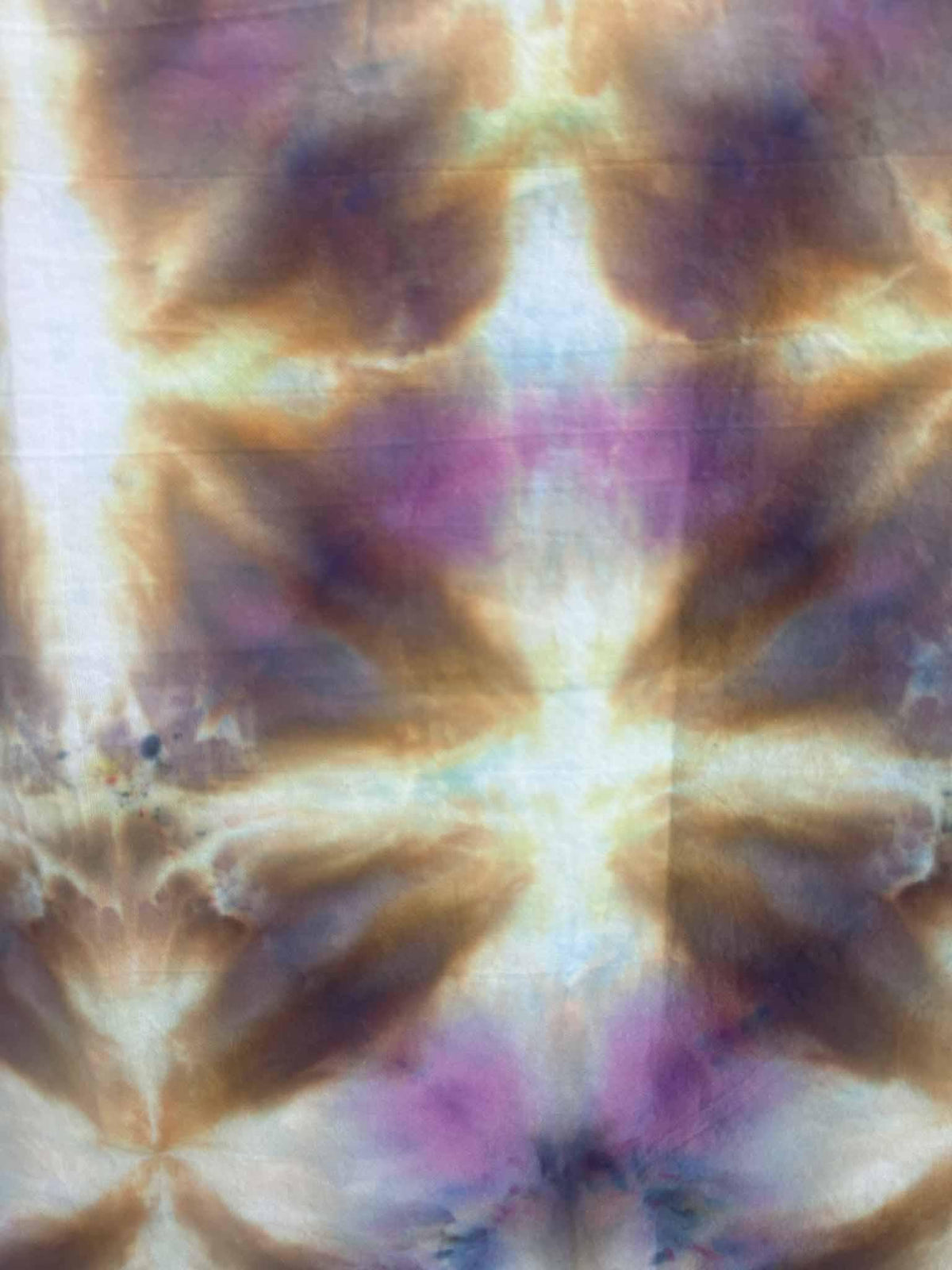 Close-up of ice dye star burst pattern in amber, purple, and blue on cotton tea towel