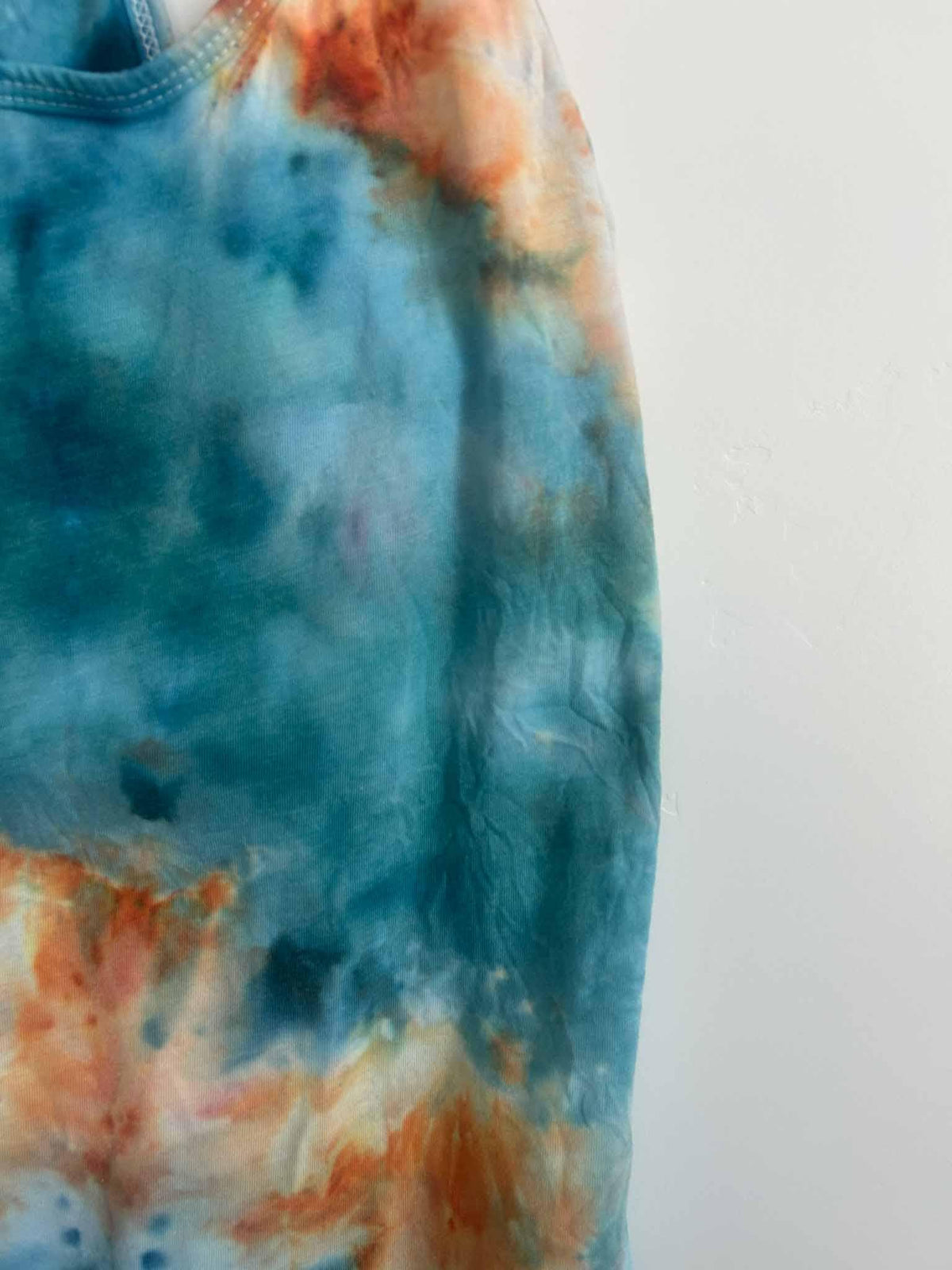Close-up of ice dye tank top side showing teal blue and peach color blending