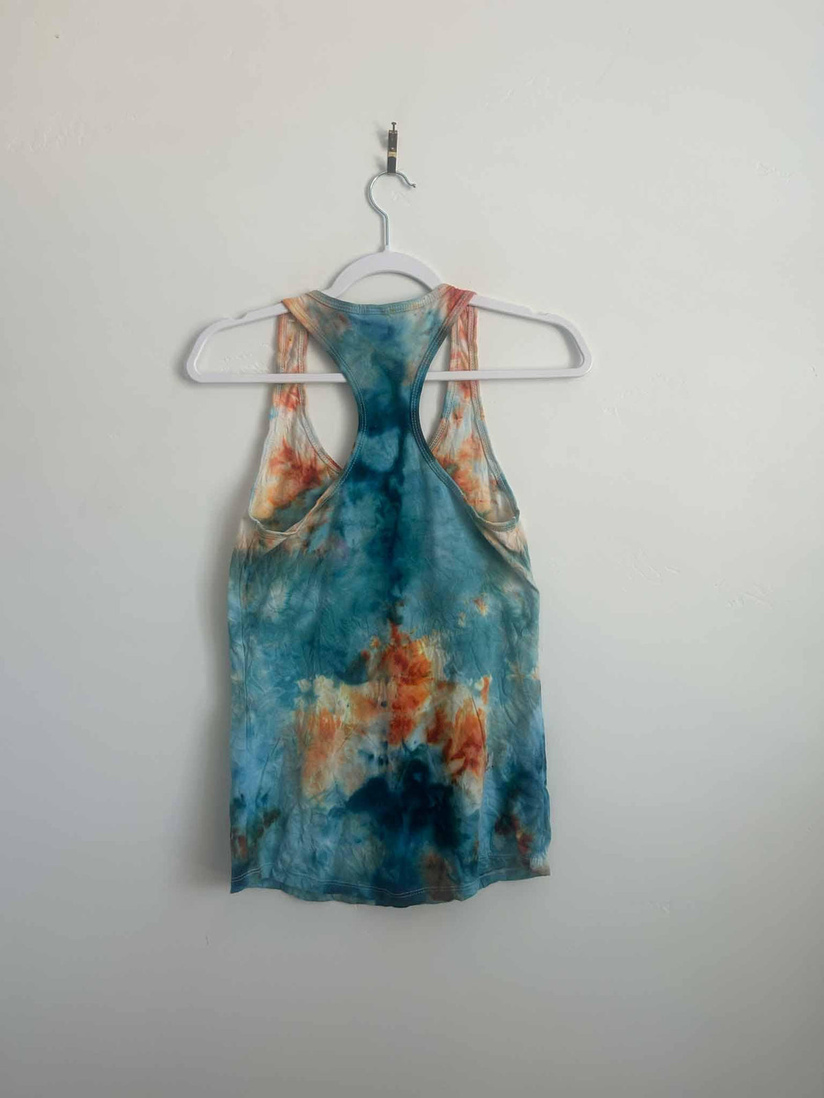 Ice dye mirror fold tank top in kingfisher blue and peach, full back view on hanger