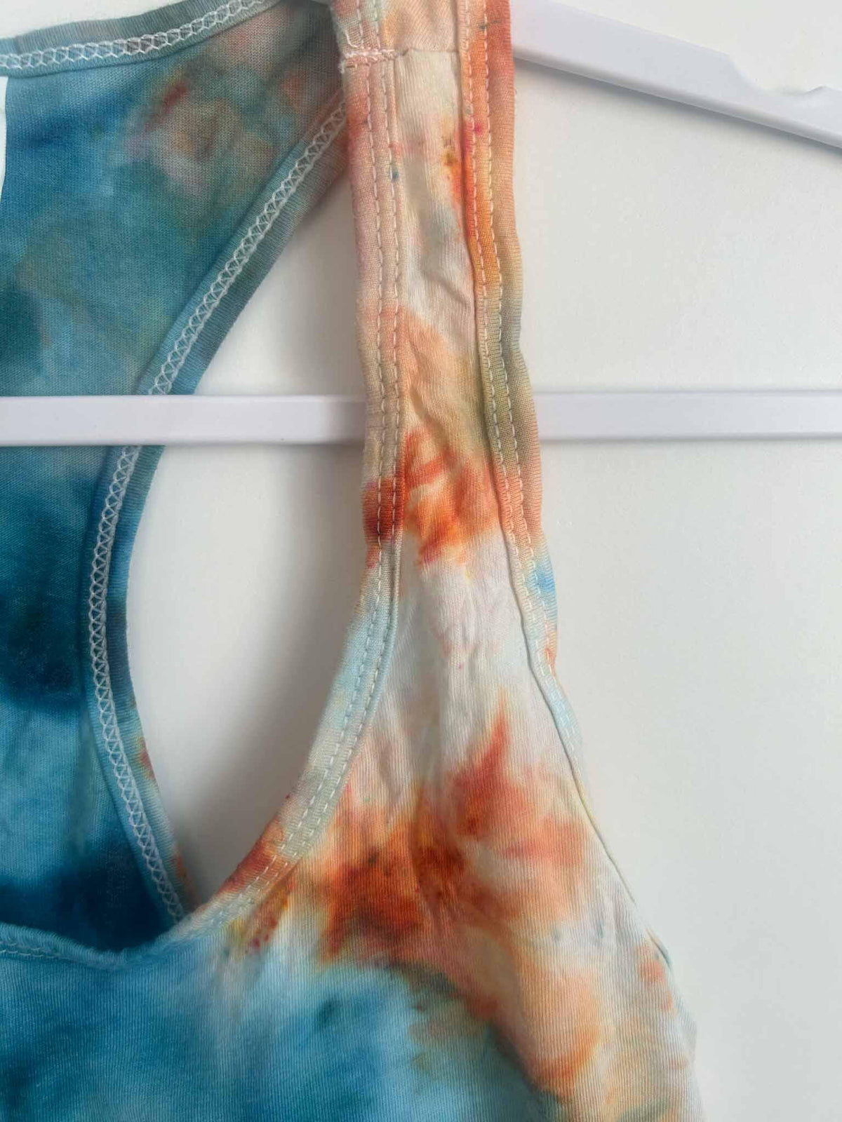 Tank top racerback strap detail with Next Level Ideal T tag in teal tie dye