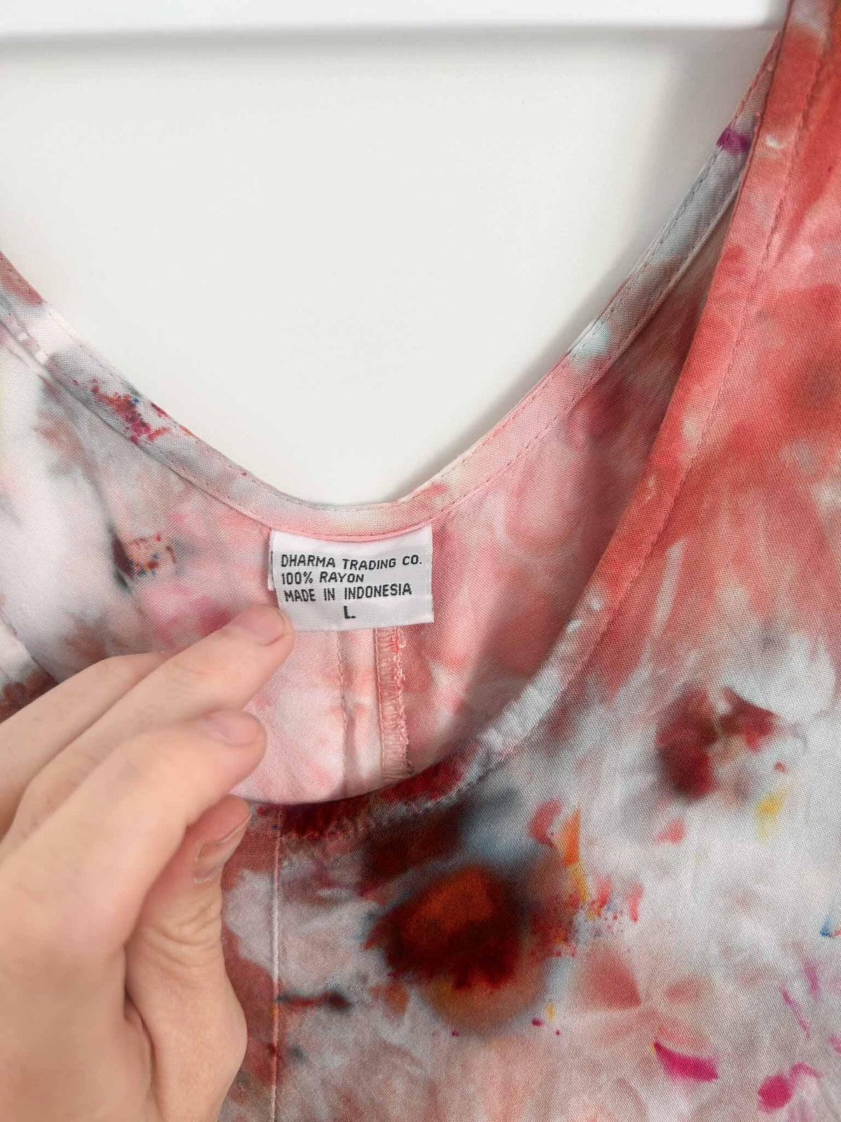 Close up of Dharma Trading Co. tag showing 100% rayon and size L inside neckline of red tie dye dress