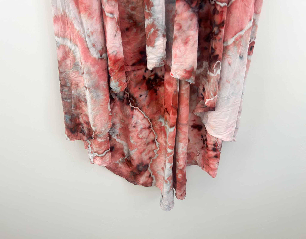 Close up of hi-lo hem on ice dyed rayon dress showing red and blush crystal pattern and asymmetrical hemline