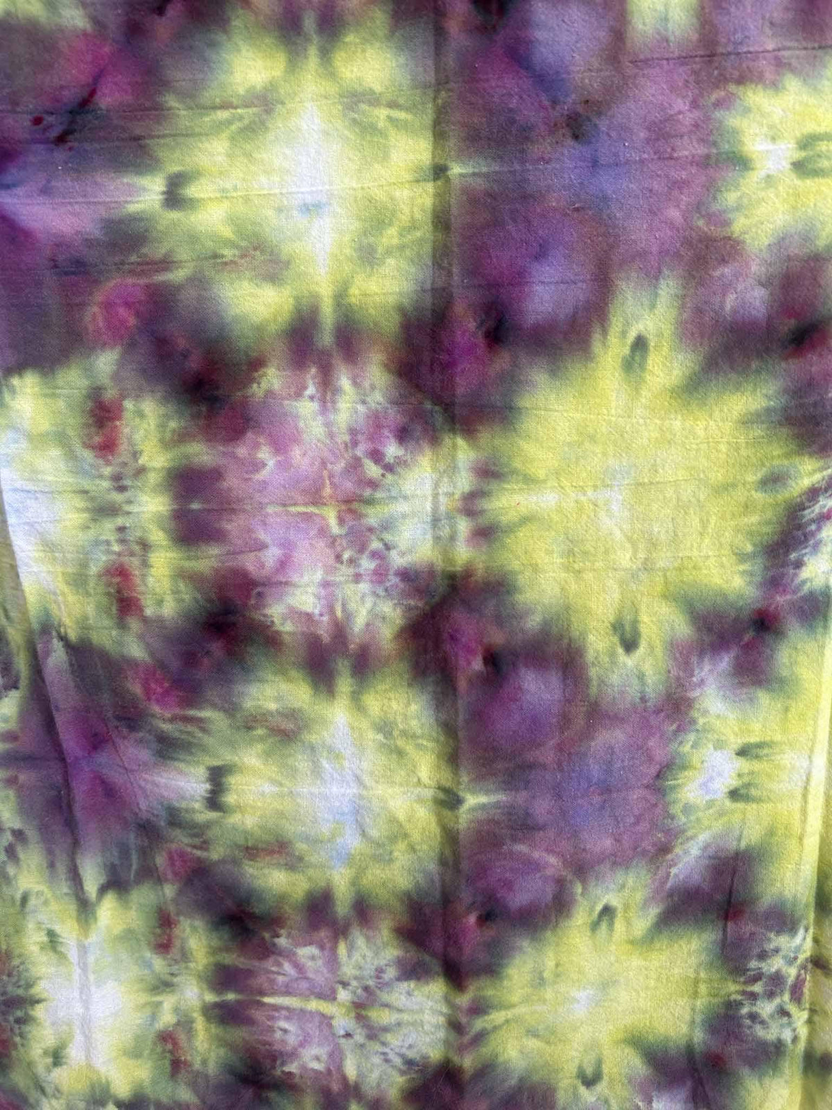 Close-up of a yellow and purple ice dye towel showing the rich plum and lime watercolor tie dye pattern.