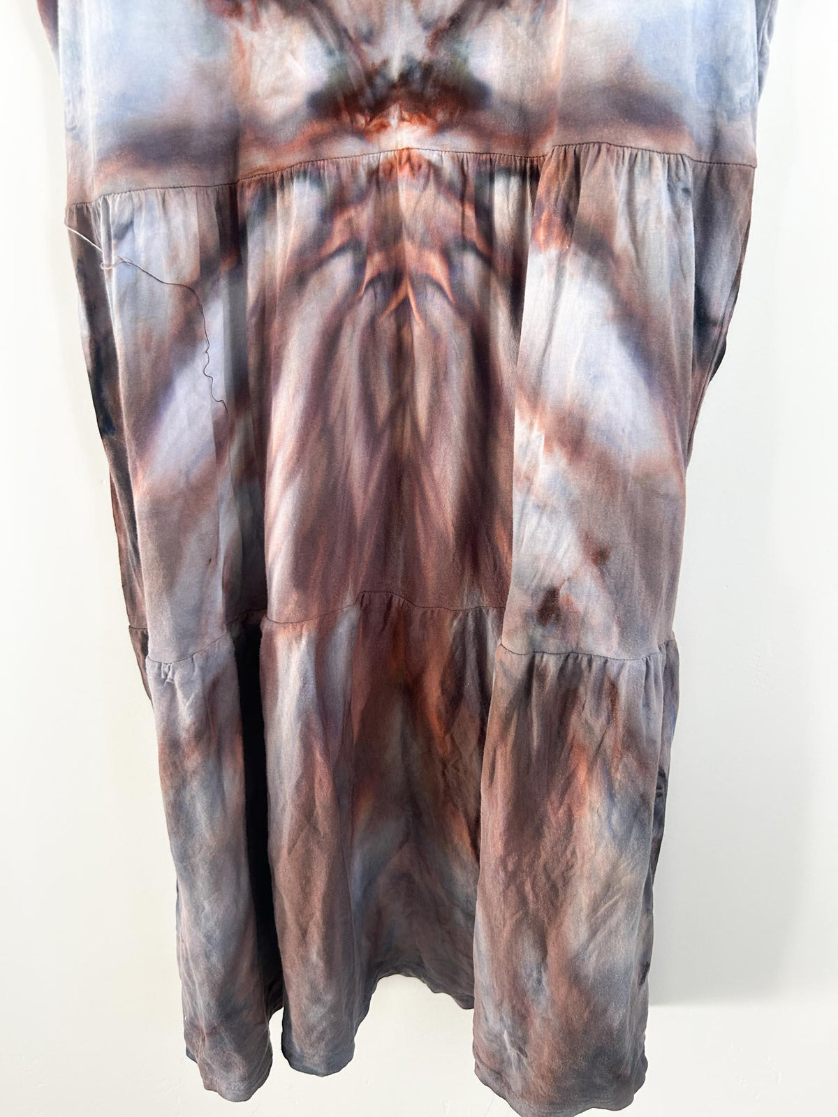 Tiered skirt detail of rust brown ice dye dress showing starburst dye pattern