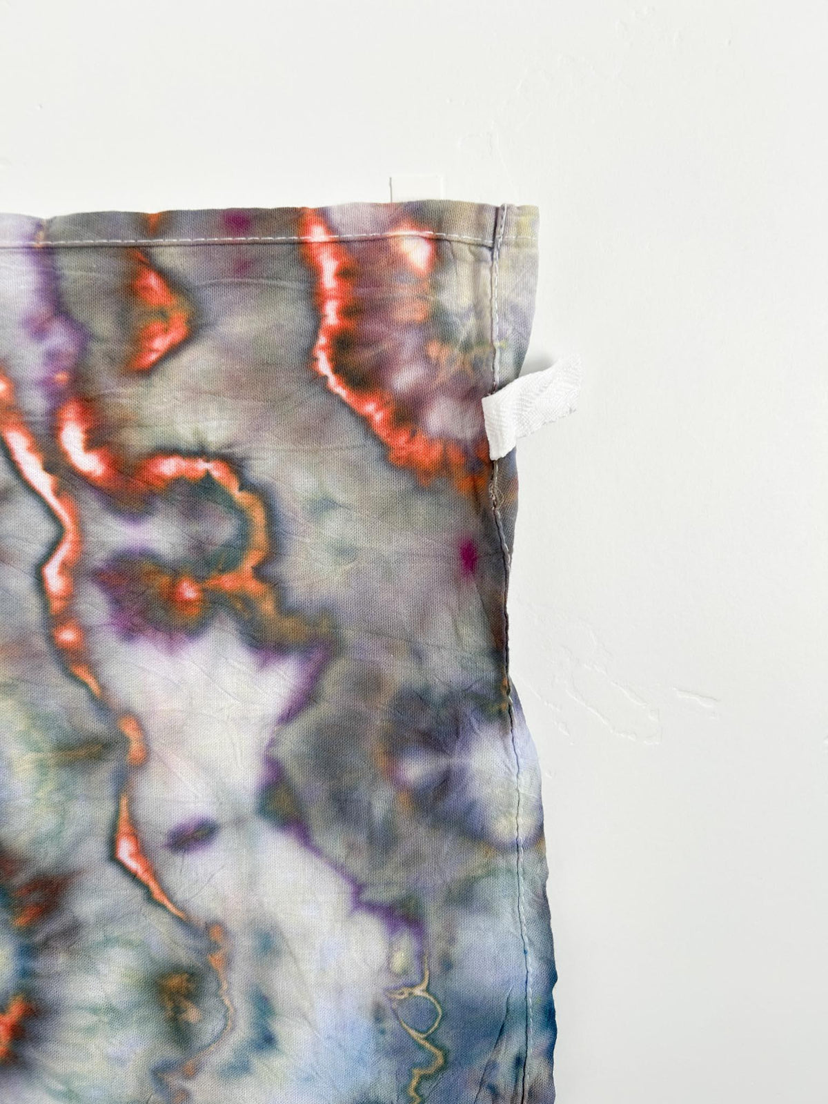 Corner detail of copper sage ice dyed tea towel showing hang loop