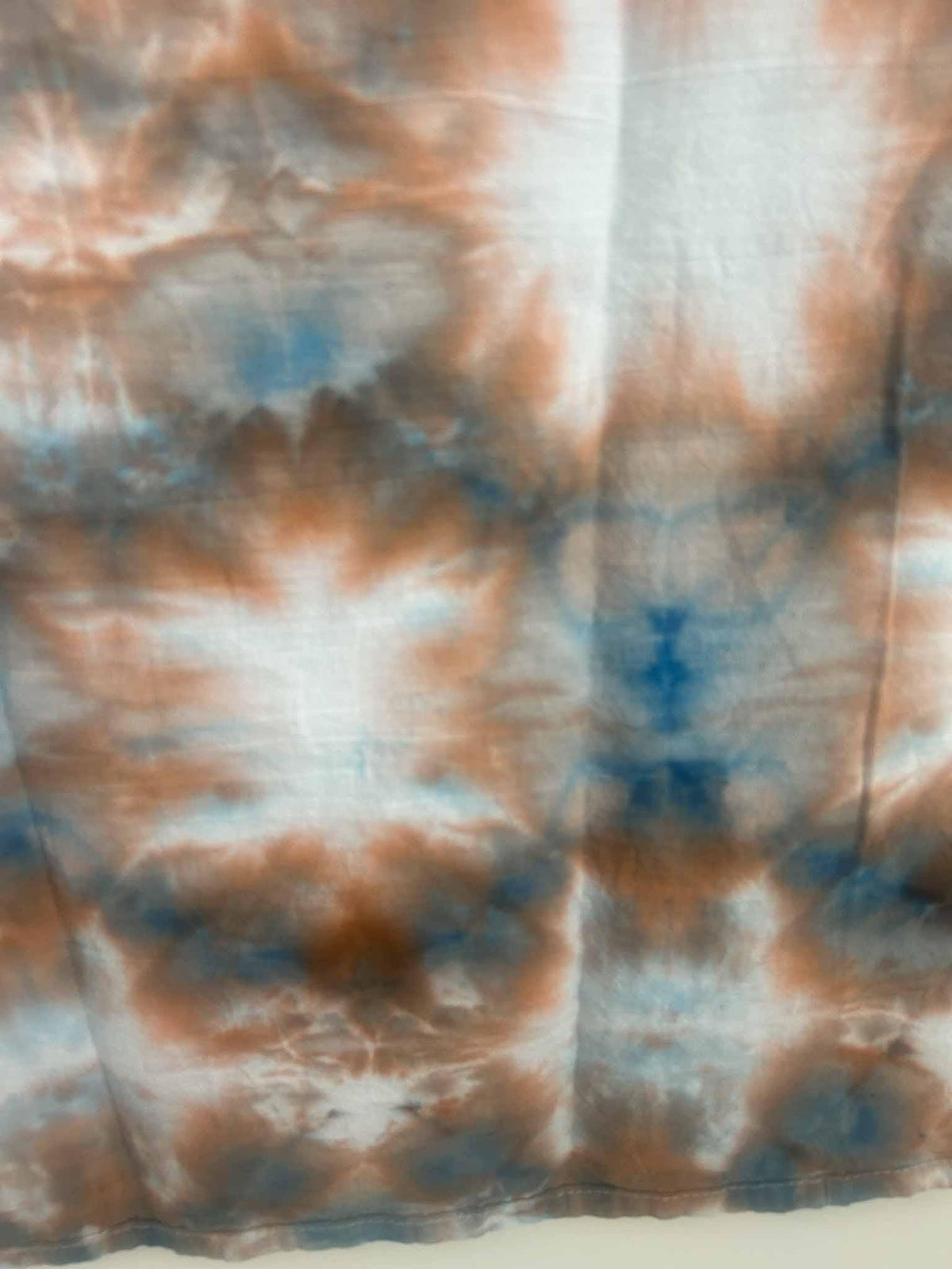 Close-up of ice dye sunburst medallions in rust, terracotta, and blue on cotton towel