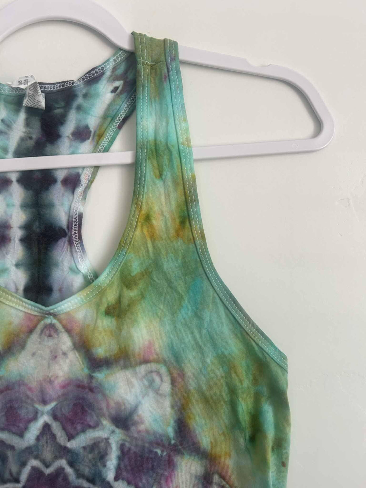 Close-up of ice dye tank top racerback strap in green and gold tie dye